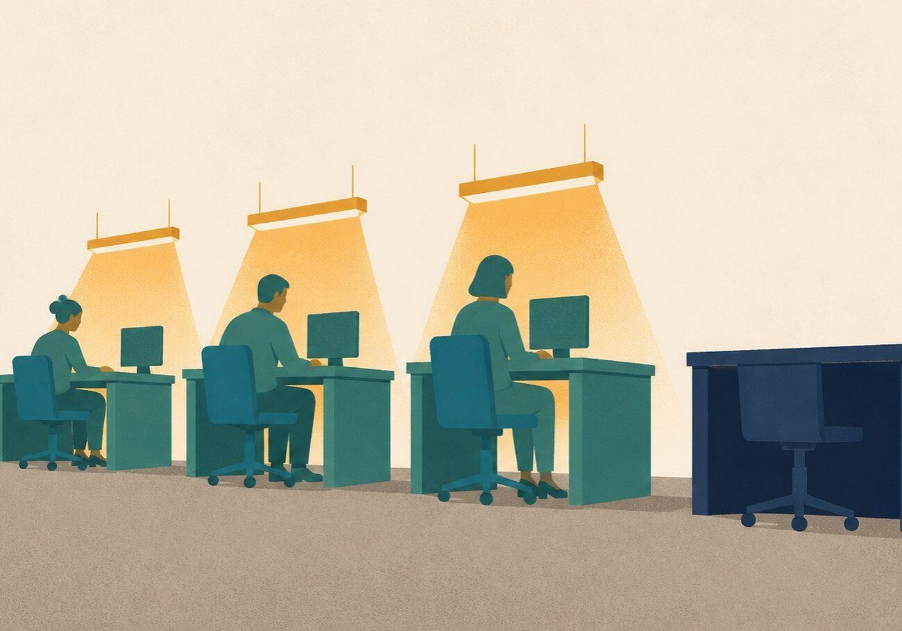 A row of warmly lit office workstations with one dark, empty desk on the right, illustrating what happens to an account when no legacy contact has been named.